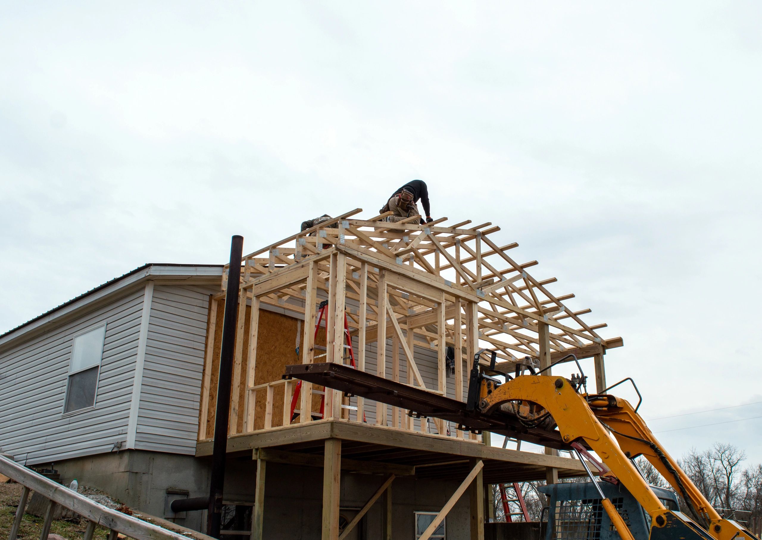 Unidentified carpenters work on the new roof, aided